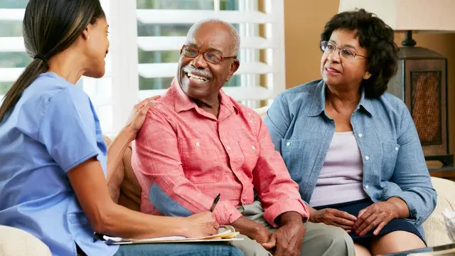 Friendly caregiver smiling next to a senior client in a cozy home environment